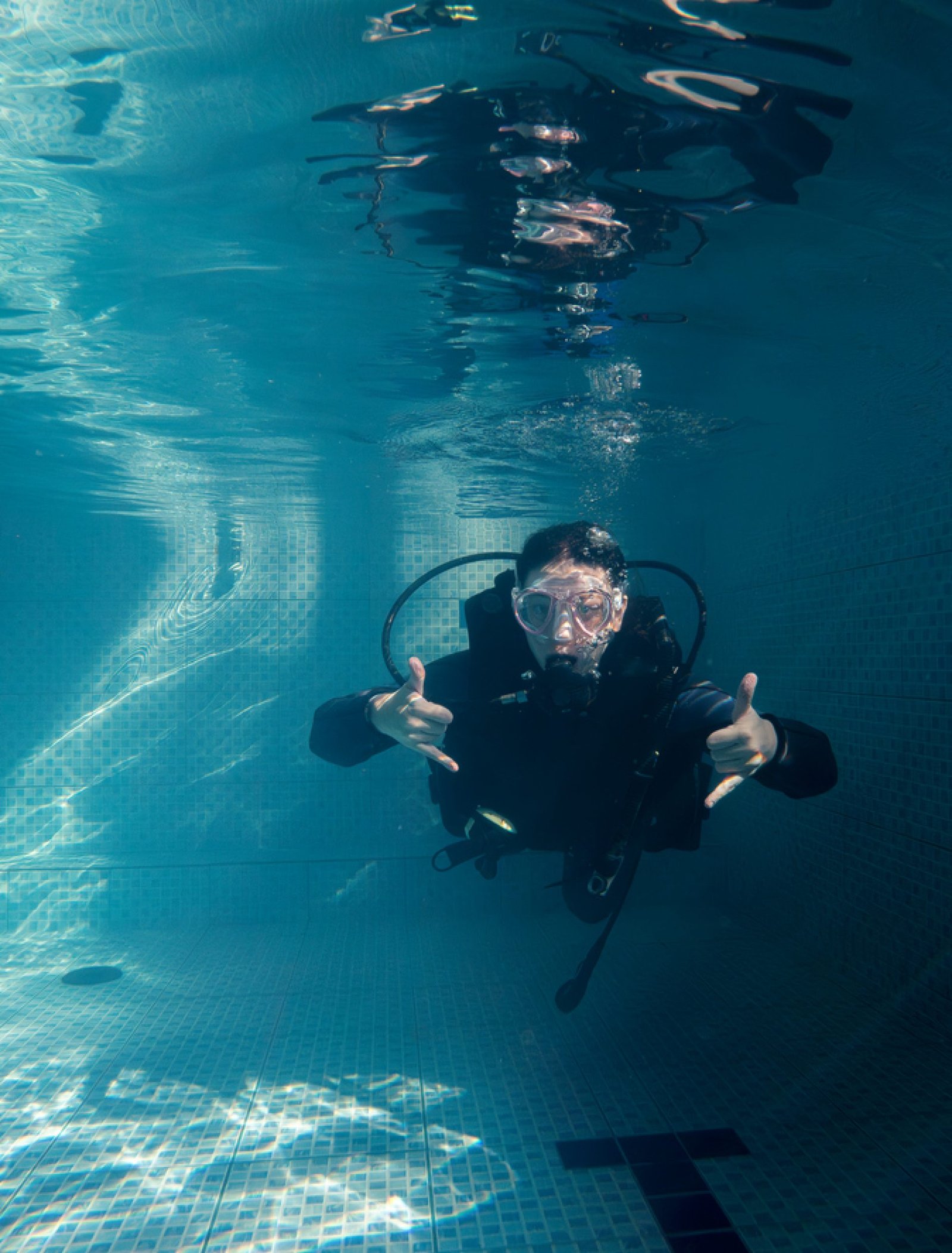 Young woman looking at camera in wetsuit while practicing in pool. Practical course in swimming pool